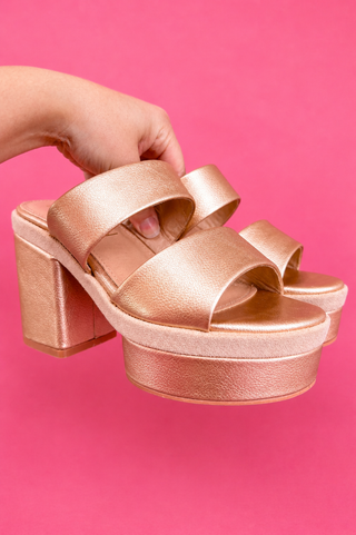 Gold platform sandal on a pink background