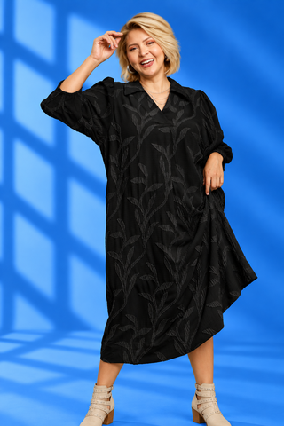 A woman modeling a black midi-length collared dress with a subtle tonal leaf pattern