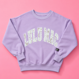 Camo Lilac Crewneck Sweatshirt with a camo appliqué, fleece-lined interior, relaxed fit, and soft cotton-blend comfort.