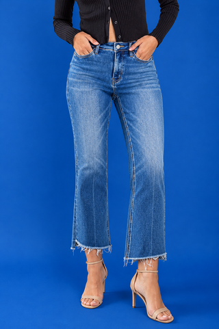 A model wearing medium-wash blue cropped flare jeans with a raw frayed hem