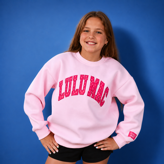 Girl wearing a pink sweatshirt with 'LULU MAC' text on a blue background