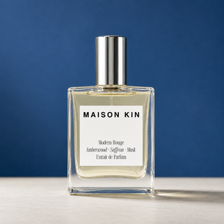 Maison Kin perfume bottle with silver cap on a blue background