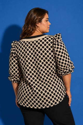 Woman wearing a polka dot blouse against a blue background