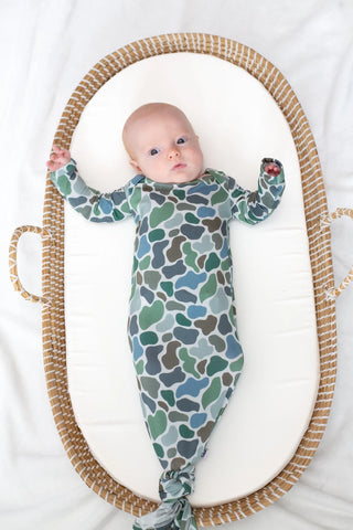 Baby wrapped in a patterned swaddle lying in a Moses basket.