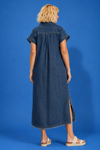 Woman wearing a long denim dress against a blue background