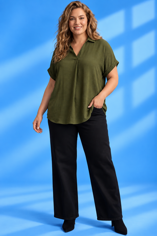A woman modeling a short-sleeve olive green blouse with a V-neck and button placket, paired with black wide-leg pants