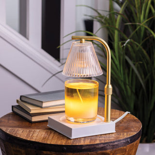 Small lamp with a glass base on a wooden table next to books and a plant