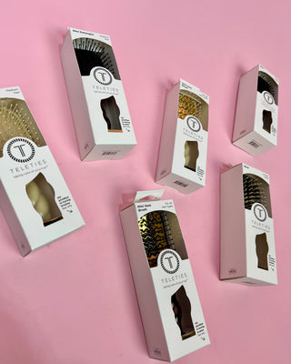 Multiple boxes of Teleties hair products on a pink background