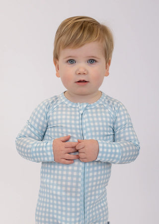 Child wearing a light blue checkered shirt against a white background