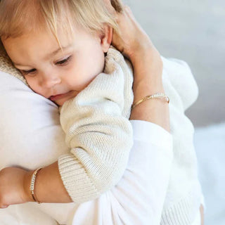 Child being comforted by an adult wearing gold bracelets