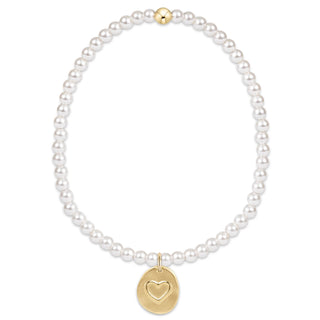 Pearl bracelet with a gold heart pendant on a white background
