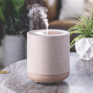 Textured diffuser emitting steam on a marble surface with plants in the background