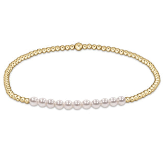 Gold beaded bracelet with white pearls on a white background
