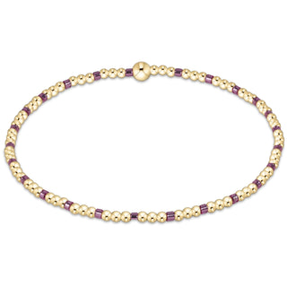 Gold and purple beaded bracelet on a white background