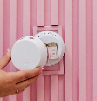 Person holding a white compact mirror with a pink background