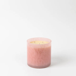 Pink candle in a glass container on a white background