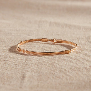 Rose gold bracelet on a beige fabric background