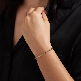 Close-up of a person wearing a gold bracelet on a dark background