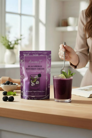 Person holding a spoon over a glass of blackberry smoothie next to a package of Lénaire Blackberry Smoothie Mix.