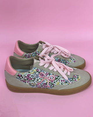 Floral-patterned sneakers with pink laces on a pink background