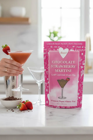 Chocolate Strawberry Martini mix package with a cocktail and strawberries on a countertop.