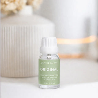 Bottle of Claire Burke home fragrance oil on a white surface with blurred background