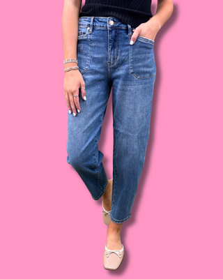 Person wearing blue jeans on a pink background