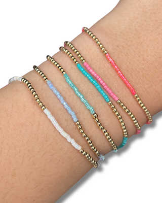 Multiple bracelets on a wrist with various colors and styles.