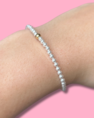 Pearl bracelet on a wrist with a pink background