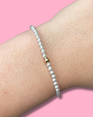 Pearl bracelet on a wrist with a pink background