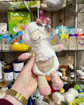 White plush toy with pink accents held by a hand in a store setting