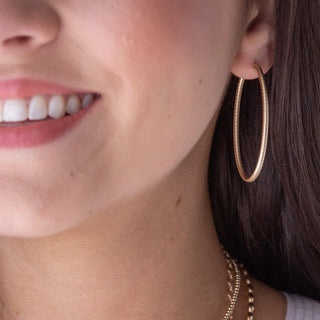Close-up of a person wearing gold hoop earrings and a necklace.
