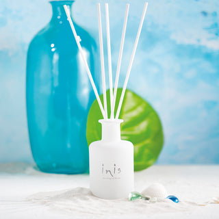 White diffuser bottle with reeds and a blue vase in the background