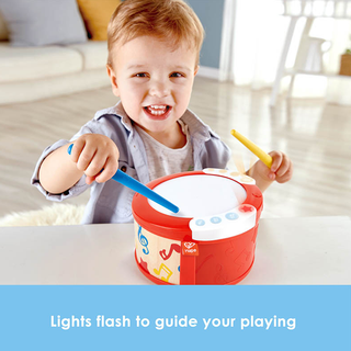 Child playing with a toy drum set in a living room.