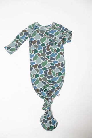 A baby long-sleeve footed sleeper with a green, blue, and brown organic pattern, featuring a knotted ankle and a small side tag, laid flat on a white background.