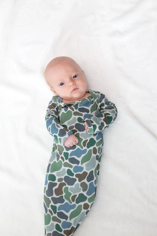 Baby swaddled in a patterned blanket on a white surface