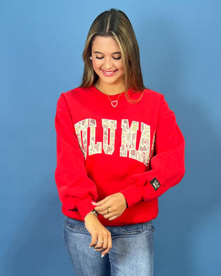 A woman modeling a bright red crewneck sweatshirt with 'LULU MAC' printed in white varsity-style letters