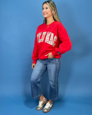 A woman modeling a bright red crewneck sweatshirt with 'LULU MAC' printed in white varsity-style letters