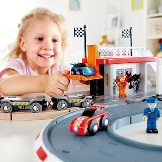 Child playing with a toy race track set in a room.