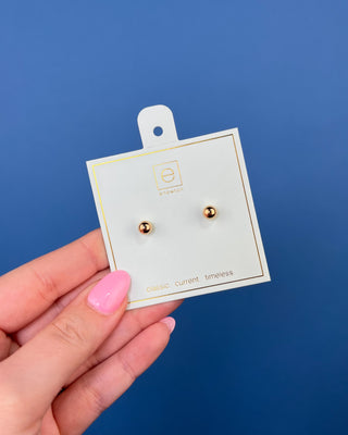 eNewton Classic Gold Ball Stud Earrings featuring polished gold-filled ball studs with secure post backs, minimalist everyday earrings shown on a jewelry card and worn in an ear piercing.