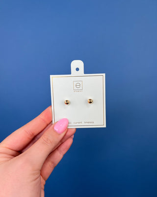 eNewton Classic Gold Ball Stud Earrings featuring polished gold-filled ball studs with secure post backs, minimalist everyday earrings shown on a jewelry card and worn in an ear piercing.