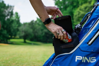 Person reaching into a blue golf bag with 'PING' branding, holding a phone.