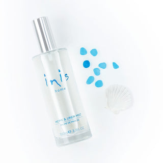 Clear spray bottle labeled 'inis home' with blue droplets on a white background