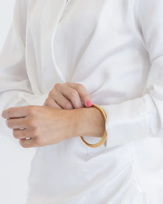 Person wearing a gold bracelet on a plain white background