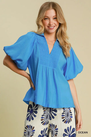 Woman wearing a blue blouse with ruffled sleeves on a beige background