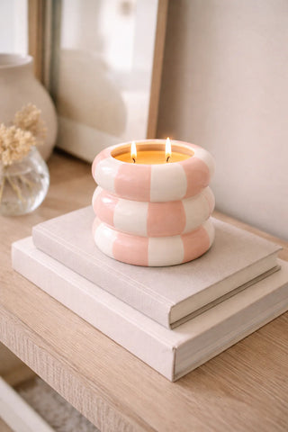 Candle in a checkered pink and white holder on a stack of books with a blurred background