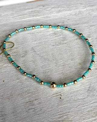 Turquoise and gold beaded bracelet on a light wooden surface