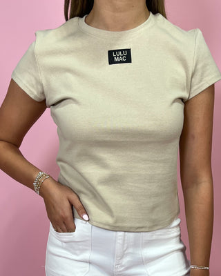 Person wearing a beige t-shirt with 'Lulu Mac' logo against a pink background
