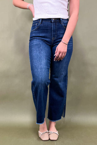 Person wearing blue jeans and a white top on a beige background