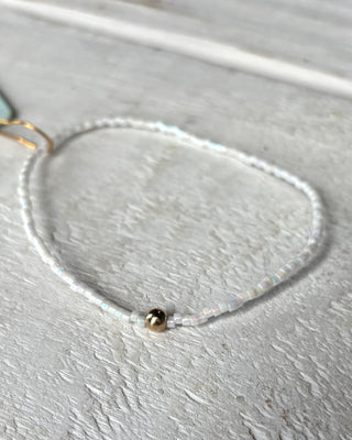 Delicate necklace with a single bead on a light gray surface